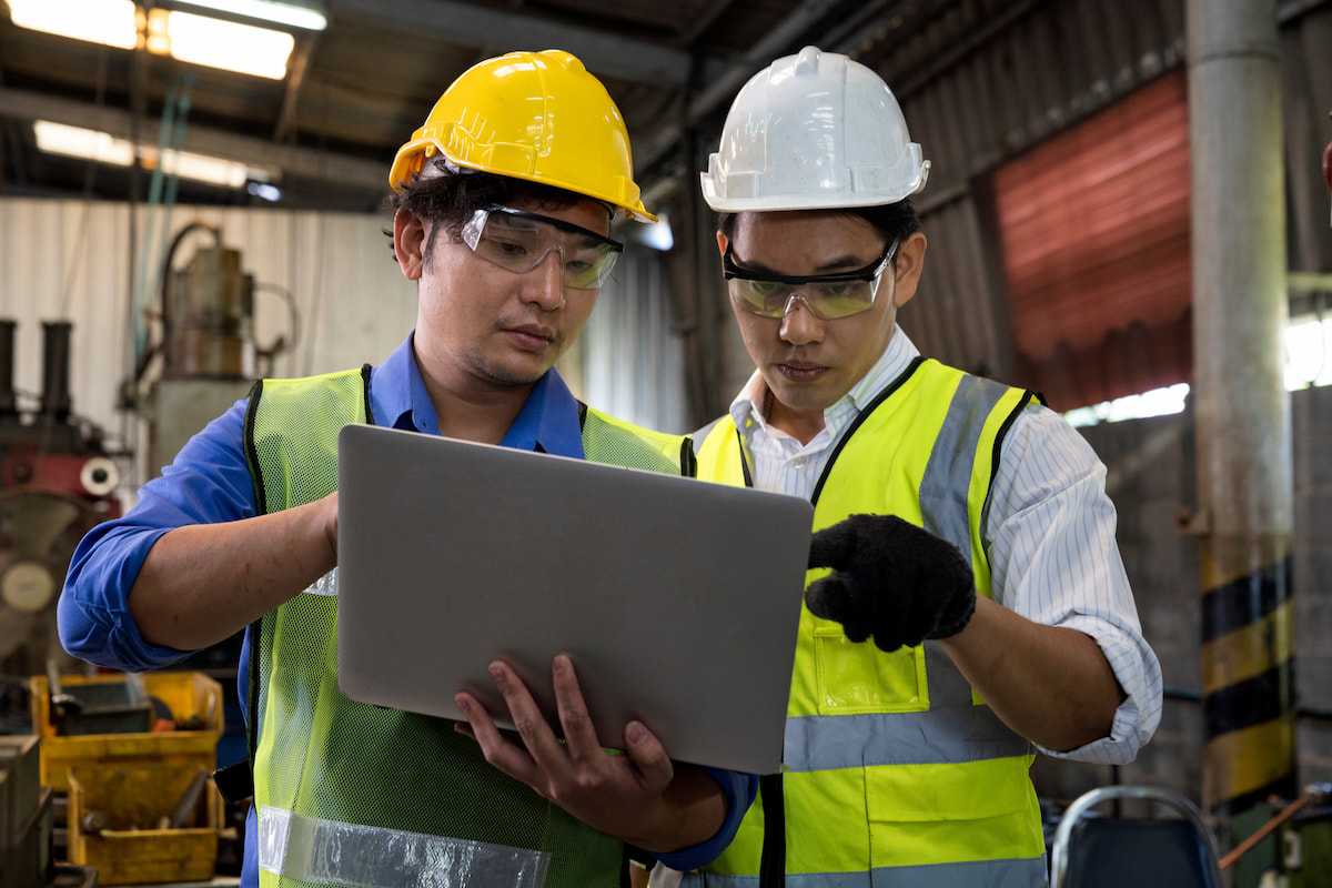 Two people looking at a laptop while working in a manufacturing facility