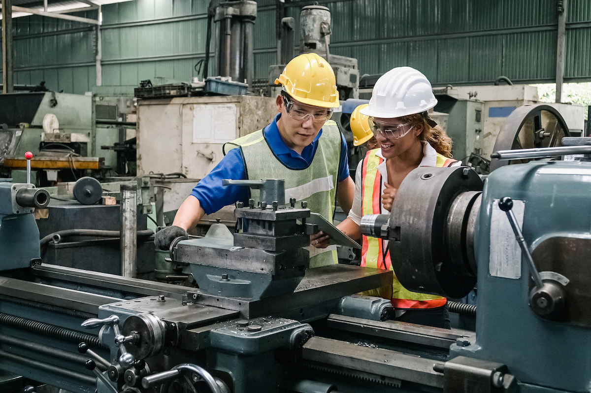 Two people performing a safety inspection on manufacturing equipment