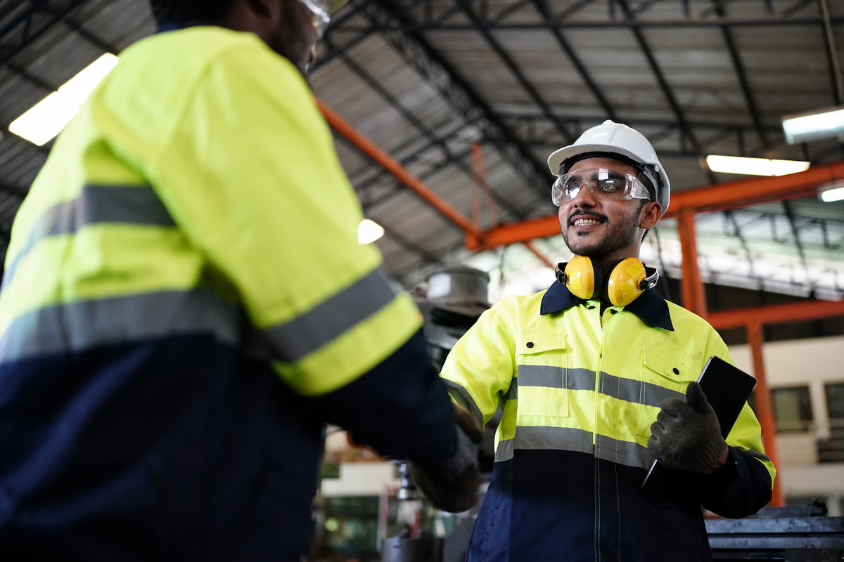 Two workers in yellow safety jackets shaking hands on a jobsite